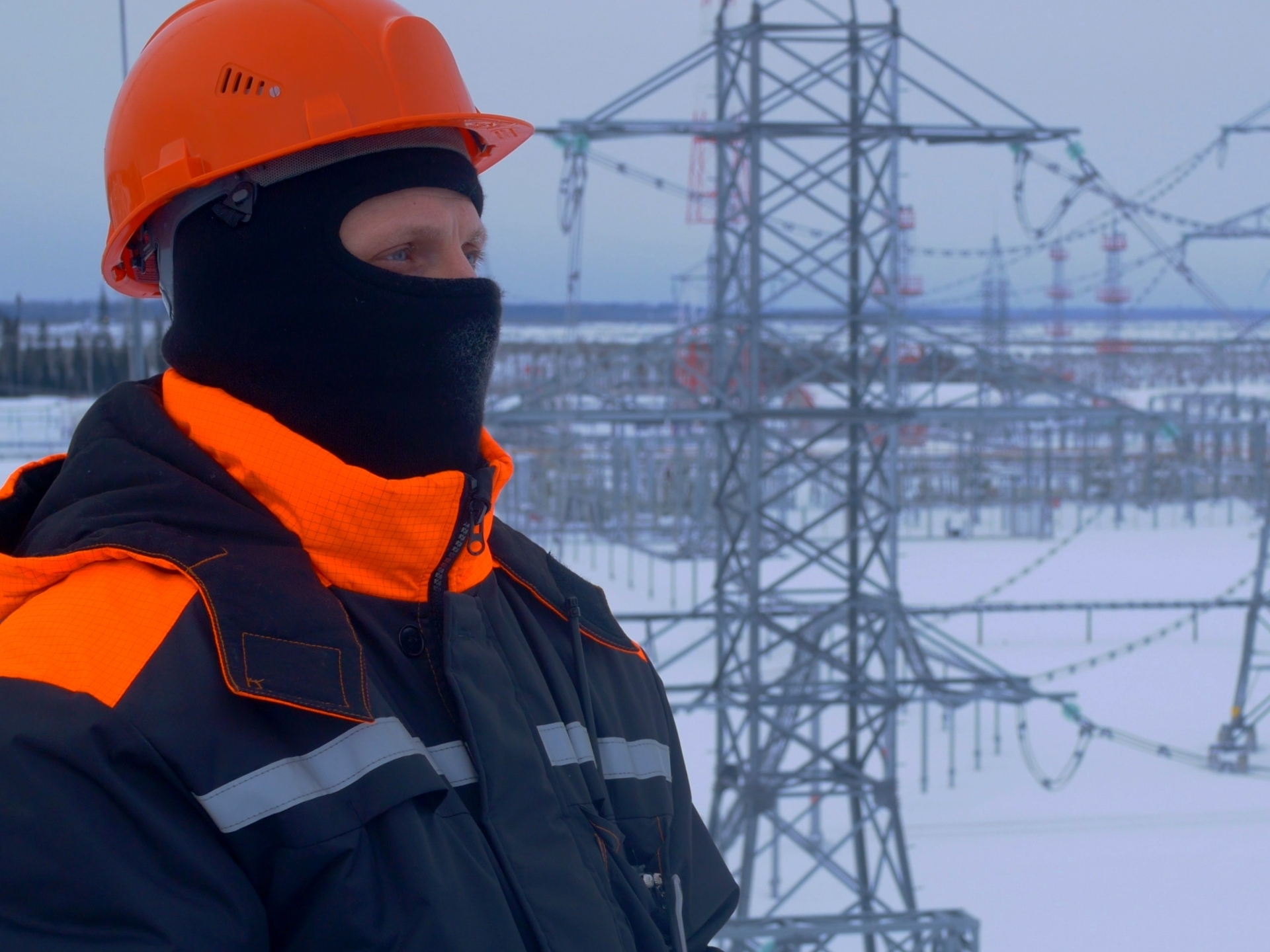 engineer in winter gear is at electricity substation equipped with walkie talkie for communication